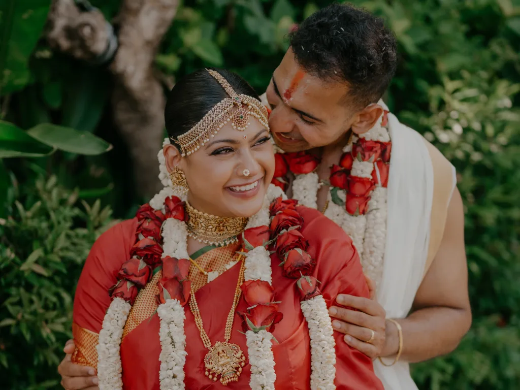 Close portrait of a bride in traditional bridal make-up, gold jewellery and floral garlands