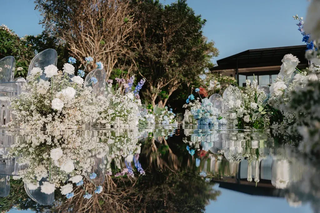Mirrored reception tablescape massed with white roses and candlelight