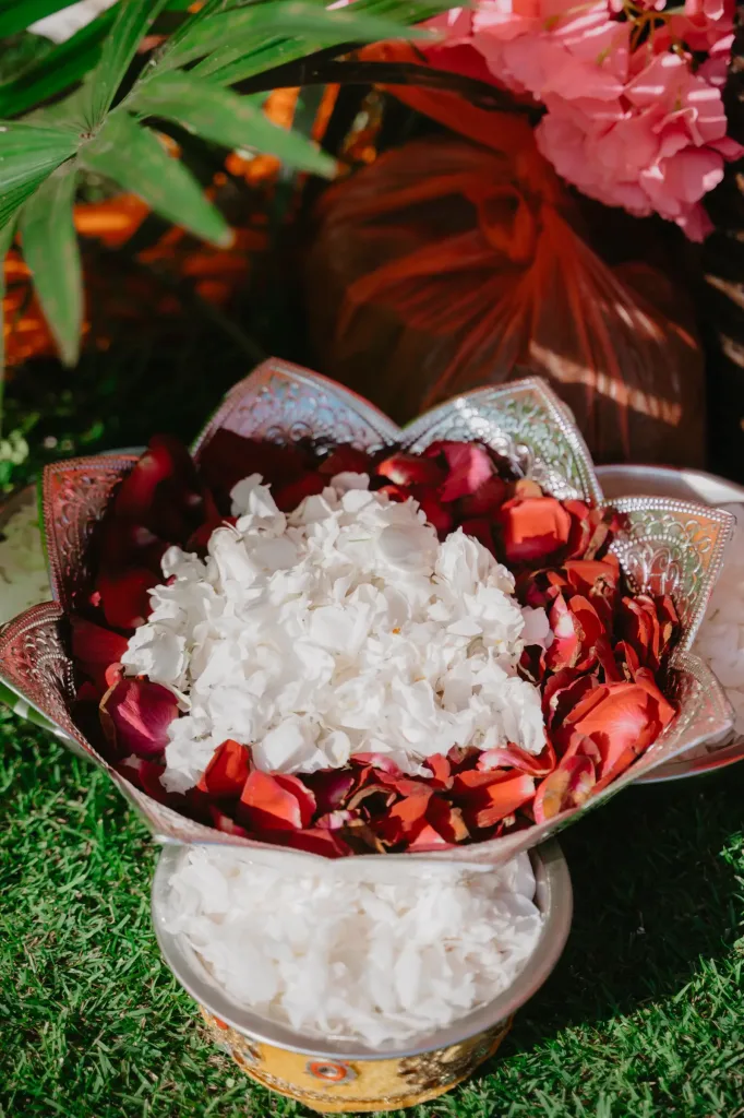 Red rose petals and rice in a brass offering bowl on the ceremony lawn