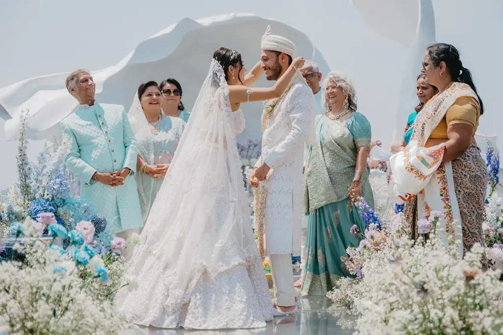 The couple under the veil during the ceremony, surrounded by pastel blooms