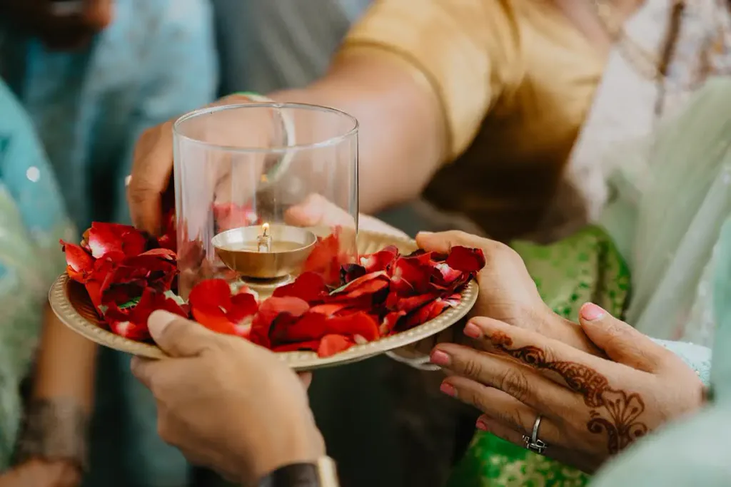 Hands passing the aarti flame during the ceremony