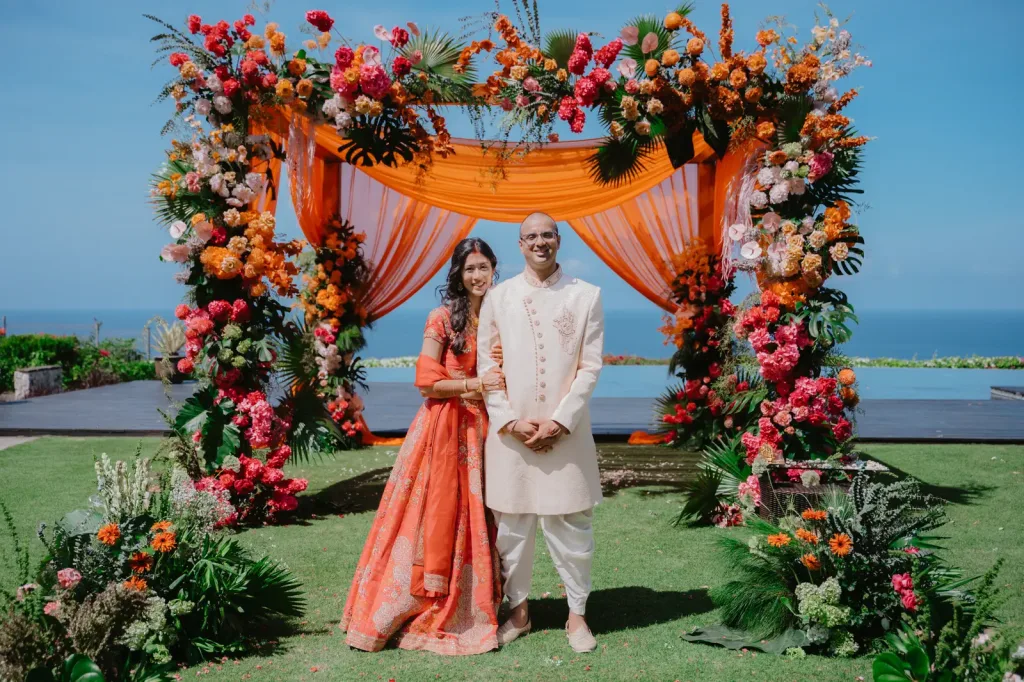 The couple beside the floral arch on the cliff edge