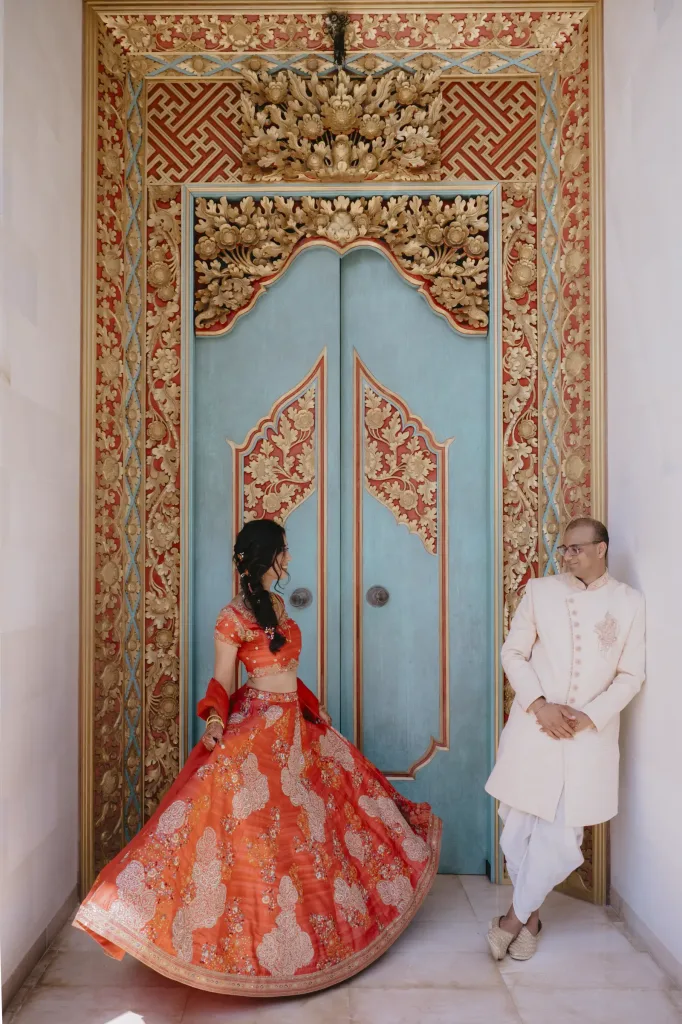 The bride in a Balinese doorway, her lehenga fanned across the step